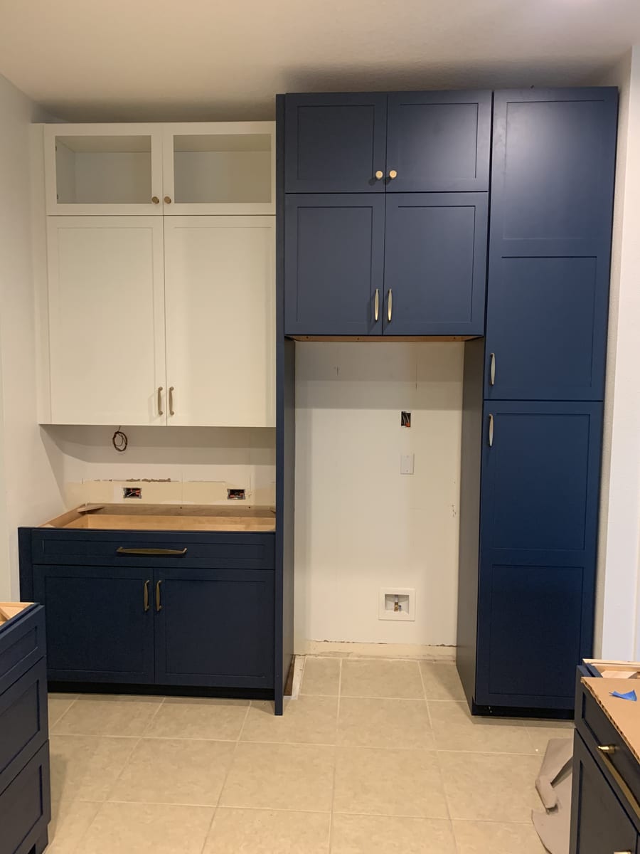 Navy built-in cabinetry with brass hardware around a laundry nook