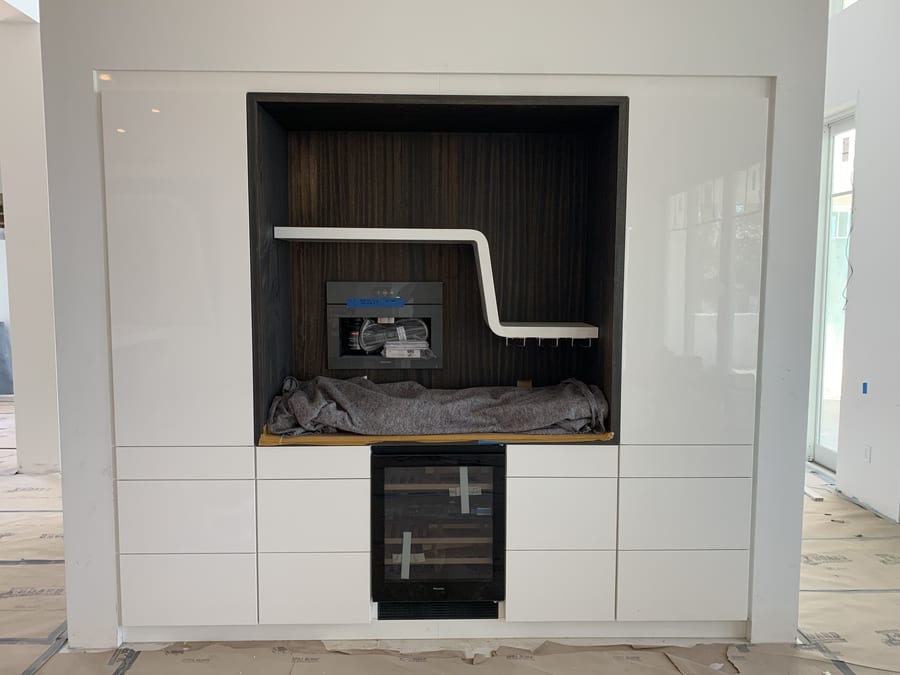 Built-in wet bar nook with a dark wood interior, floating shelf and wine fridge
