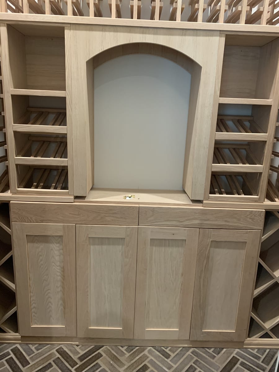 Unfinished built-in wine rack and bar cabinetry in raw wood