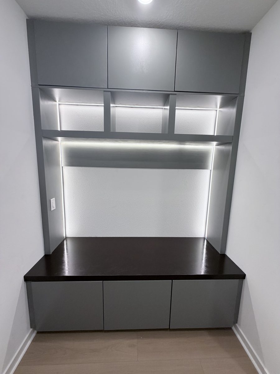 Gray built-in cabinet storage: cabinets above, drawers below a stained bench, and LED-lit open shelves