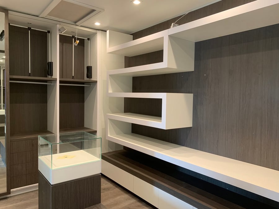 Walk-in closet with floating shelves and lit display cases