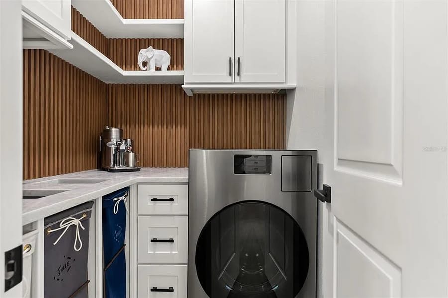 Laundry room with fluted wood shelving and a tile backsplash