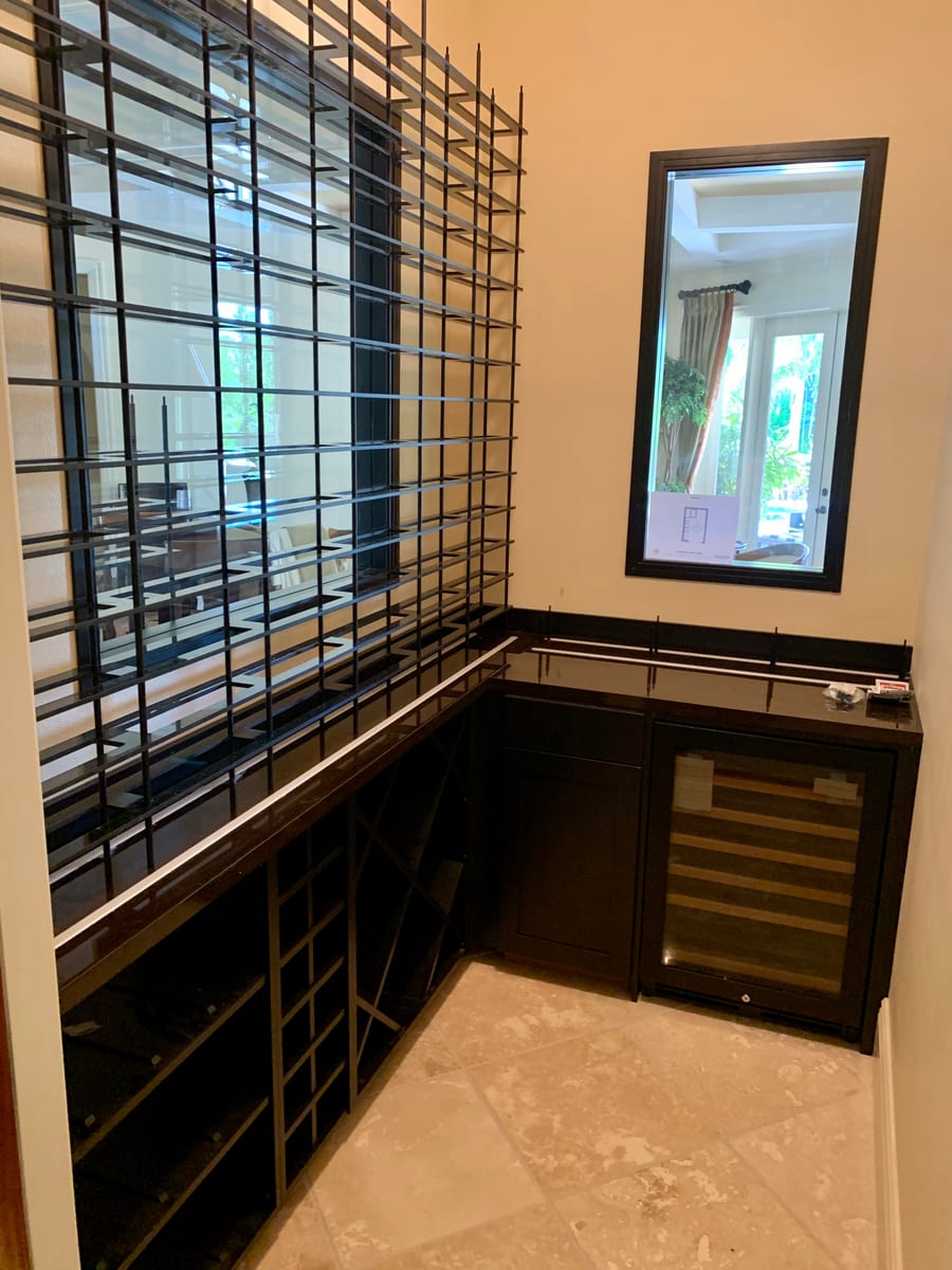 Wine cellar with a floor to ceiling black metal bottle display wall