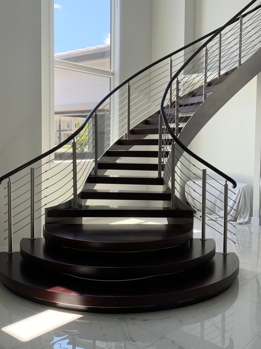 Curved staircase with dark timber treads and slim metal balusters