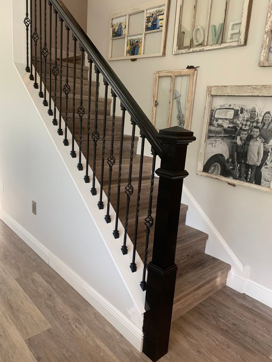 Straight staircase with a dark handrail and iron balusters