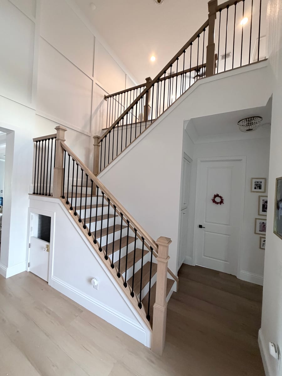 White oak staircase with black iron balusters, view down to the front entry