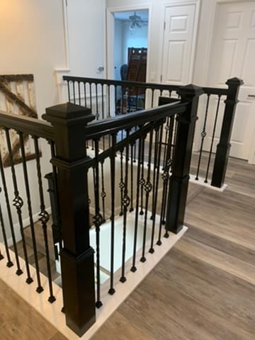 Staircase landing with black iron balusters and diamond medallion detail