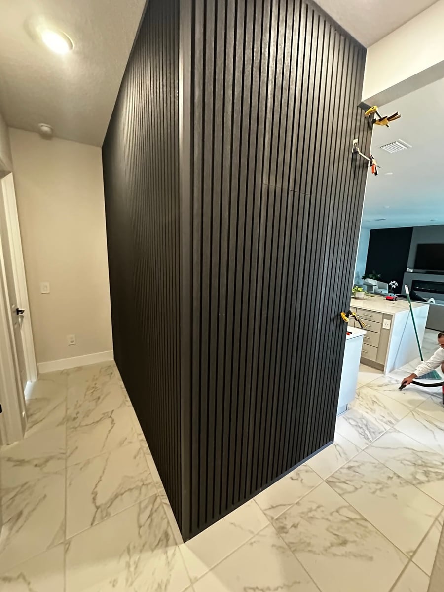 Black fluted feature wall in a marble tiled hallway