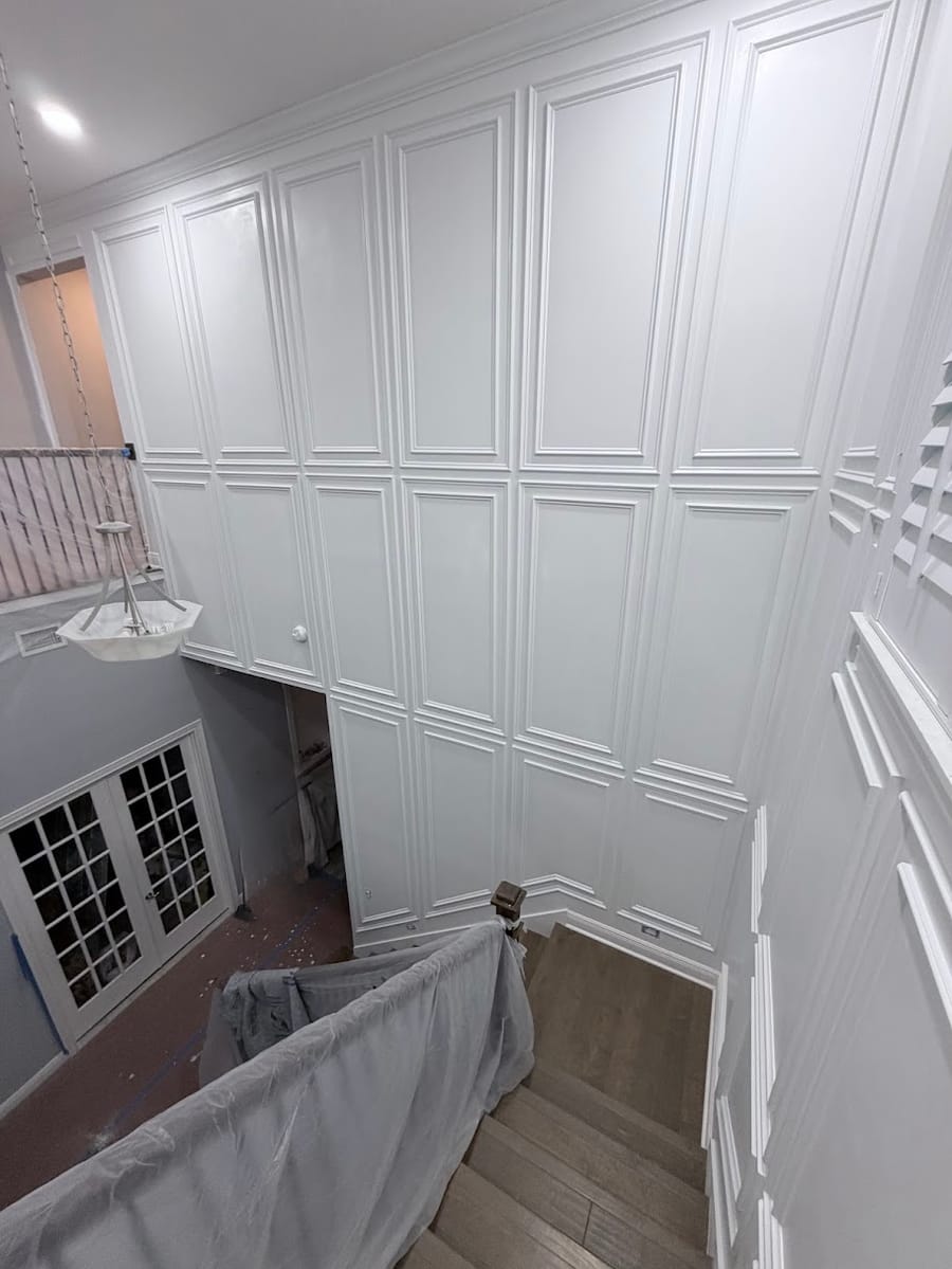 Raised panel wainscoting rising two stories above a stairwell landing