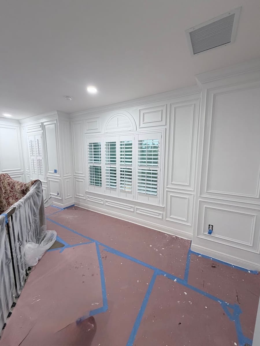 Wainscoting framing an arched window with plantation shutters