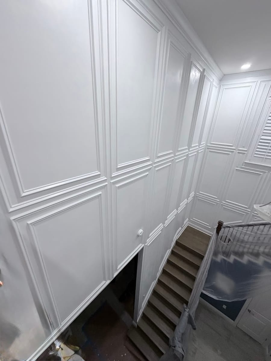 Raised panel wainscoting along a stairwell with a cased opening below