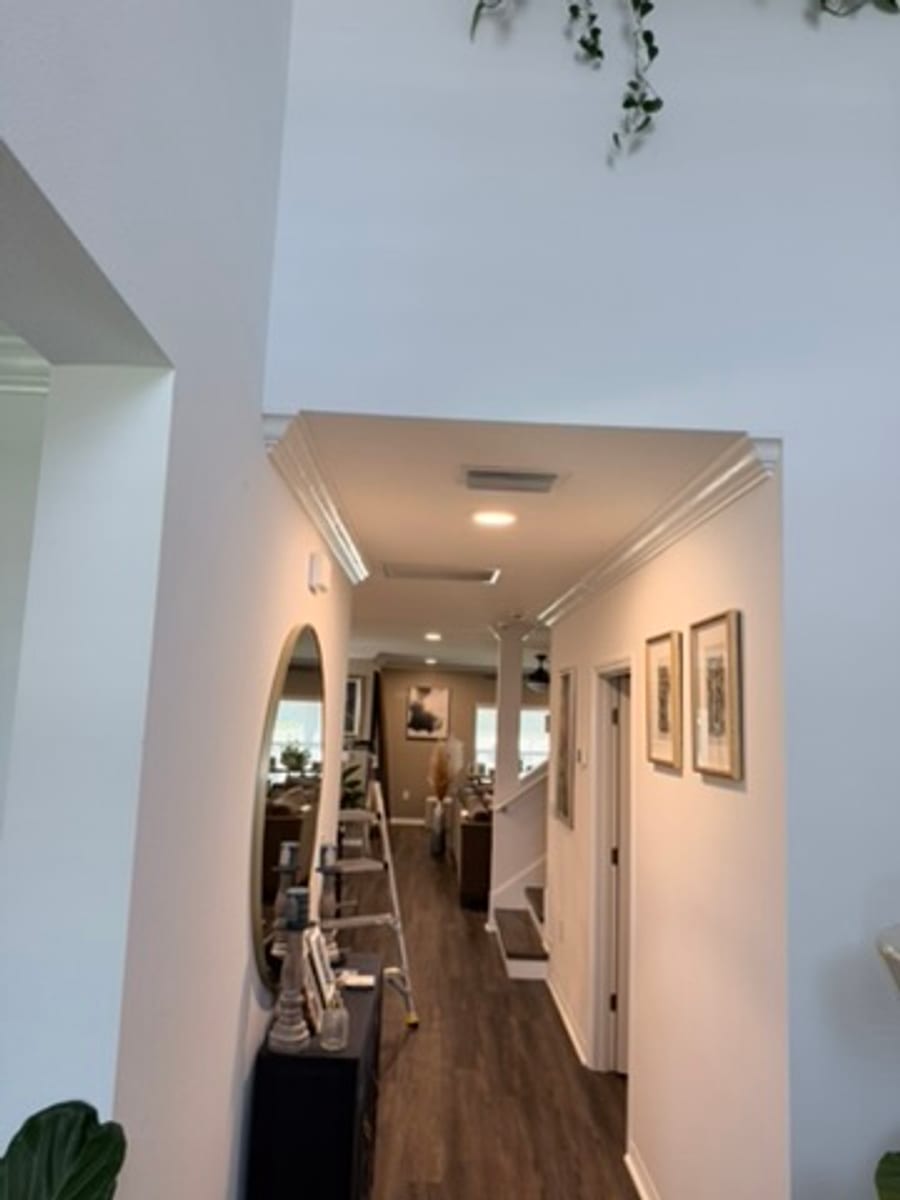 Crown molding at a hallway opening, framed art and a staircase beyond