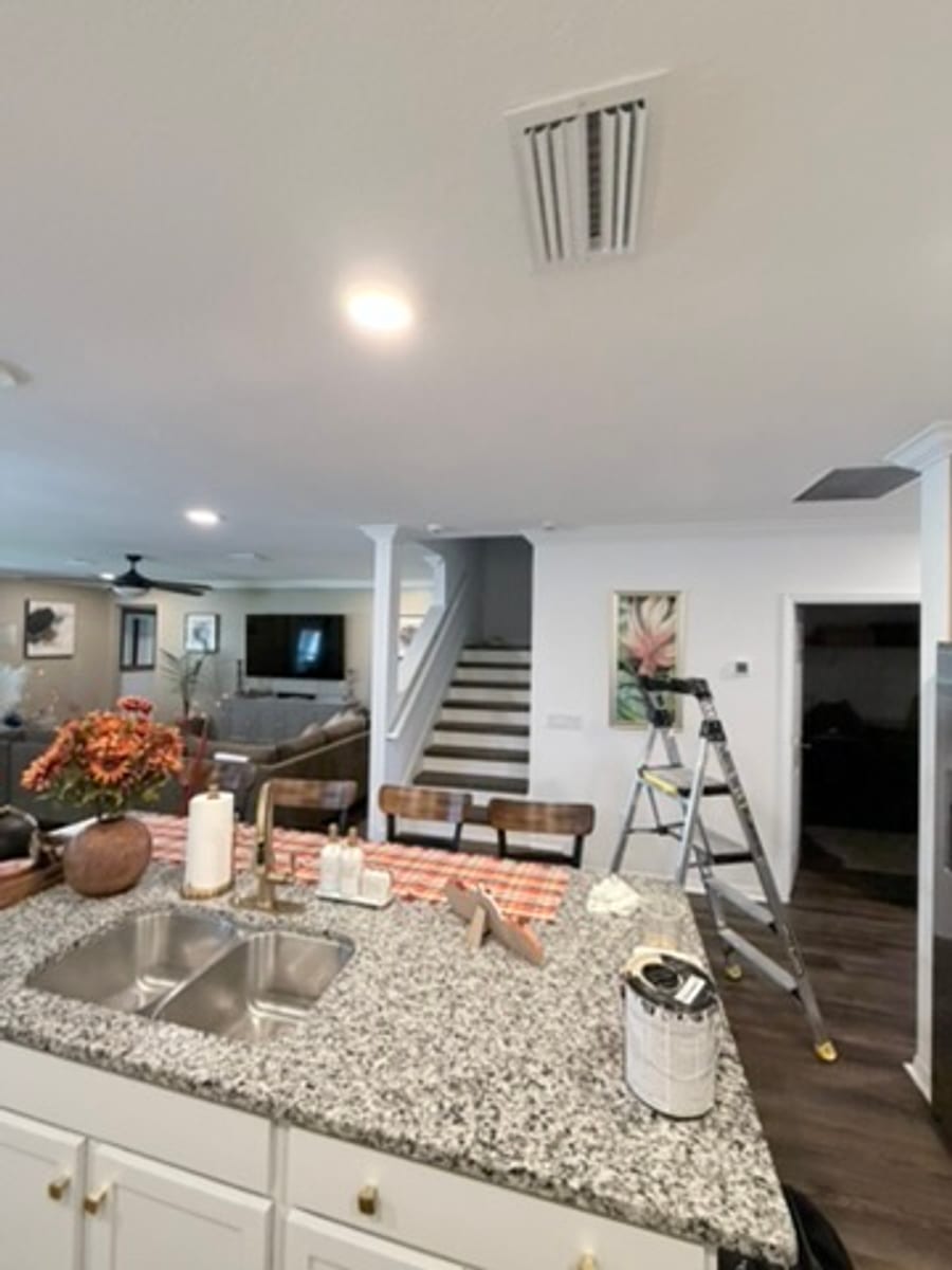 Crown molding around a ceiling vent in a kitchen and family room