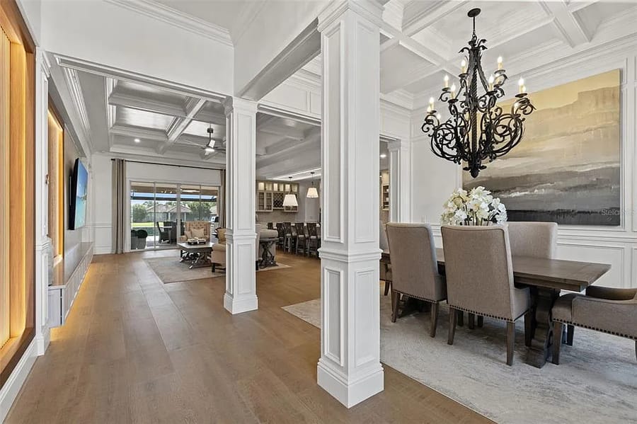 Coffered ceiling hallway with panelled columns opening to a dining room