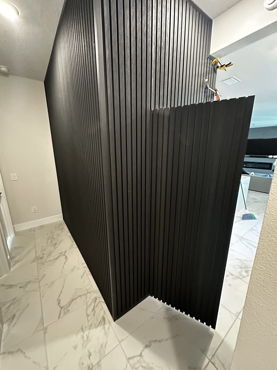 Black fluted feature wall with a hidden door built into the slat paneling