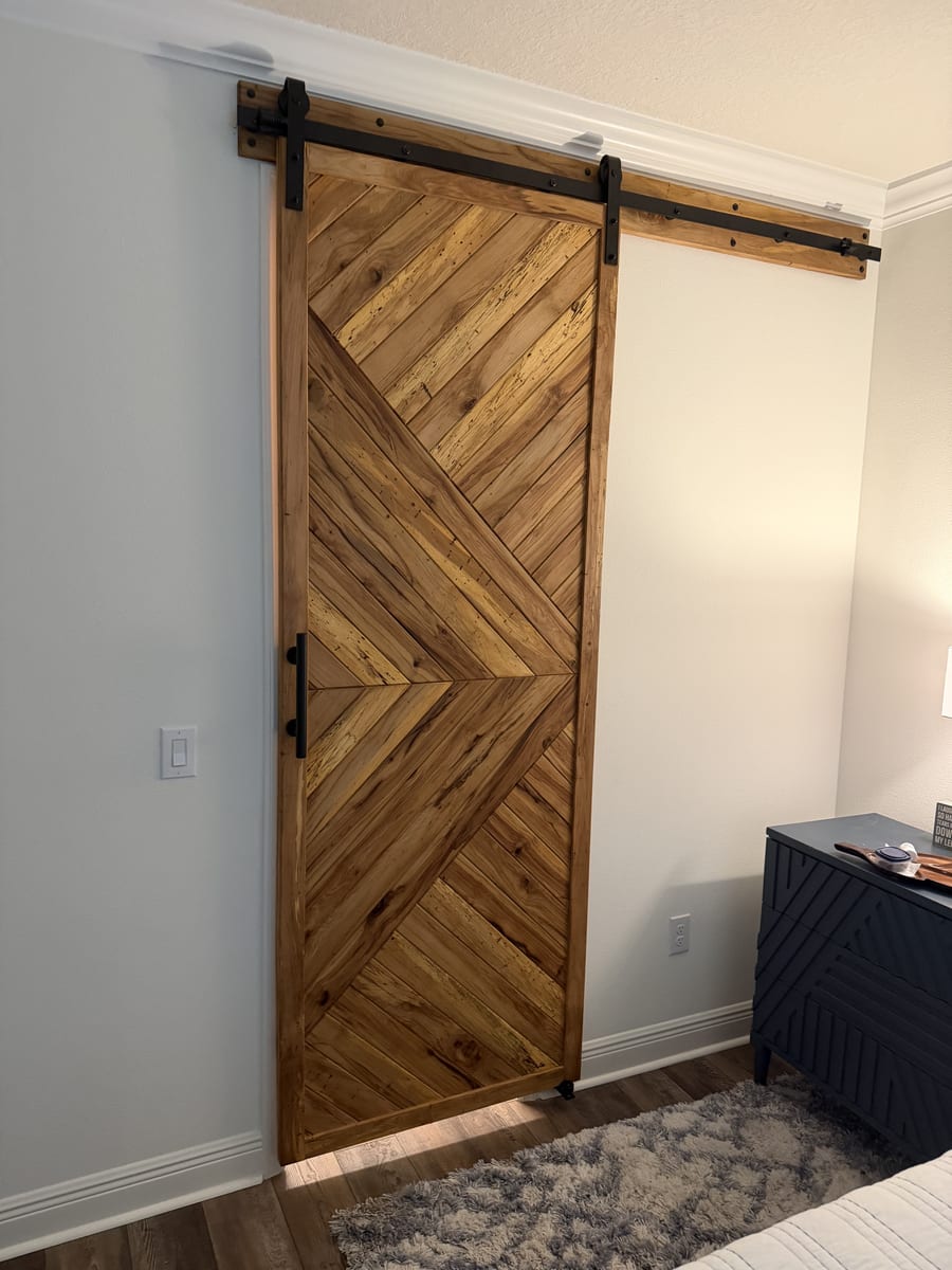 Sliding barn door in a chevron reclaimed wood pattern with black hardware