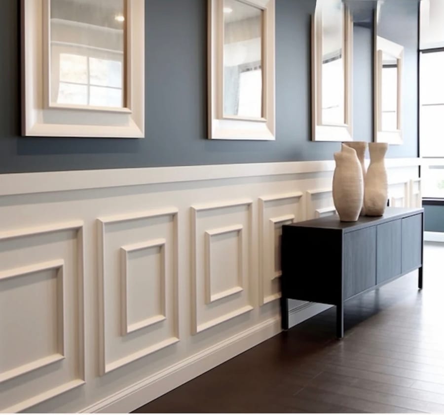 Raised panel wainscoting below framed mirrors in a hallway