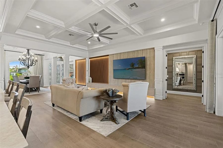 Wood slat accent wall with a mounted television beneath a coffered ceiling