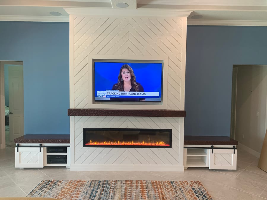Herringbone shiplap fireplace wall with a copper mantel and barn door media cabinets